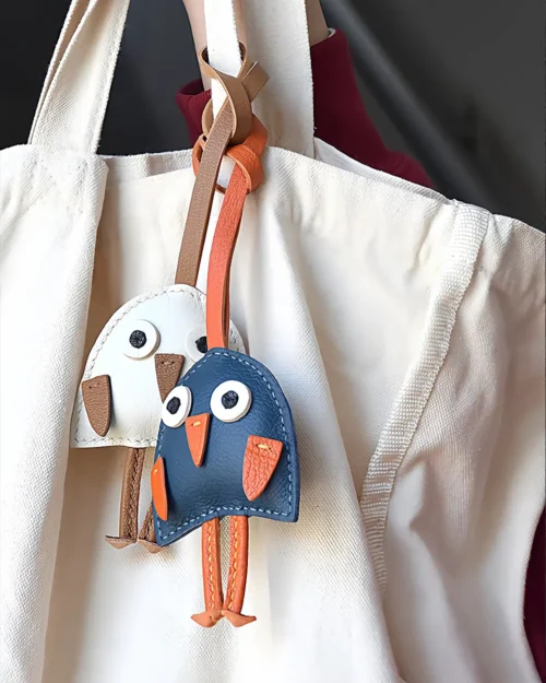 A playful bird bag charm handcrafted from French goatskin leather. Hand-stitched over three days and gift boxed for bags, keys, or car keys.