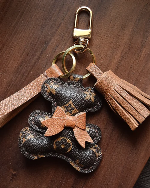 A playful bow bear bag charm handcrafted from French goatskin leather. Hand-stitched over three days and gift boxed for bags, keys, or car keys.
