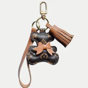 A playful bow bear bag charm handcrafted from French goatskin leather. Hand-stitched over three days and gift boxed for bags, keys, or car keys.