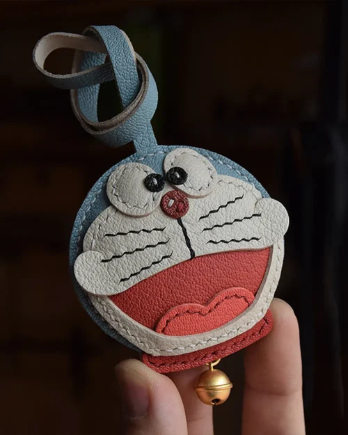 A playful Doraemon bag charm handcrafted from French goatskin leather. Hand-stitched over three days and gift boxed, perfect for bags, keys, or car keys.