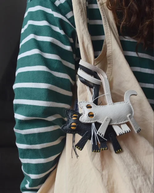 A playful cat bag charm handcrafted from French goatskin leather. Hand-stitched over three days and gift boxed for bags, keys, or car keys.