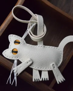 A playful cat bag charm handcrafted from French goatskin leather. Hand-stitched over three days and gift boxed for bags, keys, or car keys.