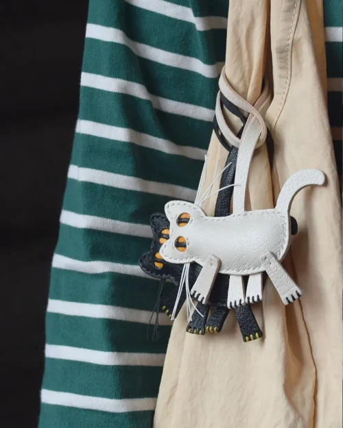 A playful cat bag charm handcrafted from French goatskin leather. Hand-stitched over three days and gift boxed for bags, keys, or car keys.