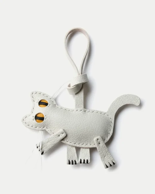 A playful cat bag charm handcrafted from French goatskin leather. Hand-stitched over three days and gift boxed for bags, keys, or car keys.