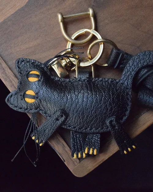 A playful cat bag charm handcrafted from French goatskin leather. Hand-stitched over three days and gift boxed for bags, keys, or car keys.