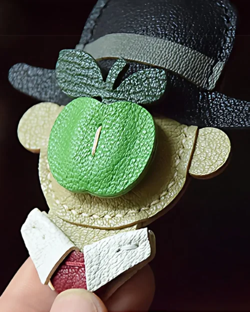 A surreal apple gentleman bag charm handcrafted from premium leather. Hand-stitched over three days and gift boxed for bags, keys, or car keys.