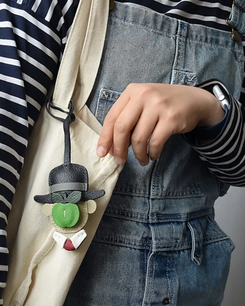 A surreal apple gentleman bag charm handcrafted from premium leather. Hand-stitched over three days and gift boxed for bags, keys, or car keys.