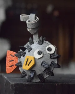 A whimsical pufferfish bag charm handcrafted from French goatskin leather. Hand-stitched over three days and gift boxed for bags, keys, or car keys.