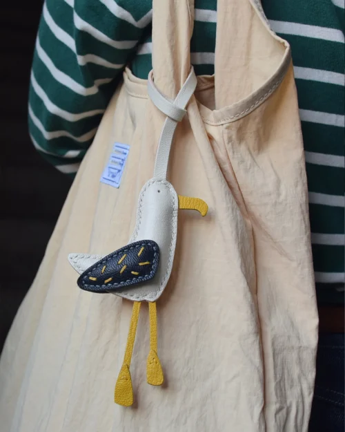 A whimsical seagull bag charm handcrafted from French goatskin leather. Hand-stitched over three days and gift boxed for bags, keys, or car keys.