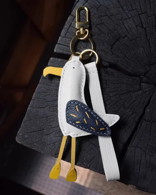 A whimsical seagull bag charm handcrafted from French goatskin leather. Hand-stitched over three days and gift boxed for bags, keys, or car keys.