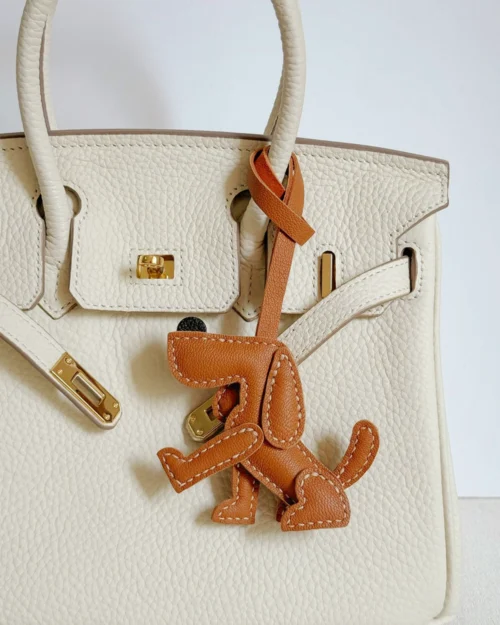 A playful dog bag charm handcrafted from French goatskin leather. Hand-stitched over three days and gift boxed, perfect for bags, keys, or car keys.