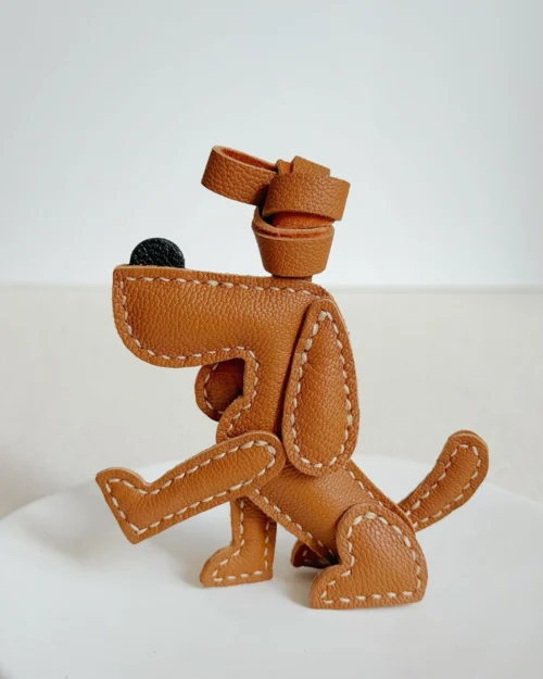 A playful dog bag charm handcrafted from French goatskin leather. Hand-stitched over three days and gift boxed, perfect for bags, keys, or car keys.