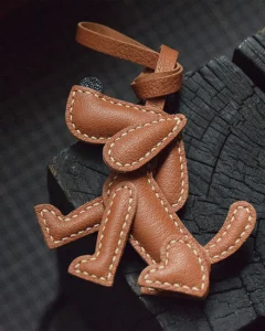 A playful dog bag charm handcrafted from French goatskin leather. Hand-stitched over three days and gift boxed, perfect for bags, keys, or car keys.