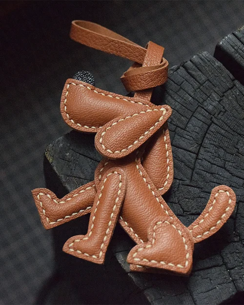 A playful dog bag charm handcrafted from French goatskin leather. Hand-stitched over three days and gift boxed, perfect for bags, keys, or car keys.