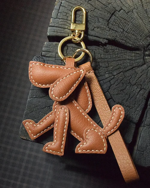 A playful dog bag charm handcrafted from French goatskin leather. Hand-stitched over three days and gift boxed, perfect for bags, keys, or car keys.