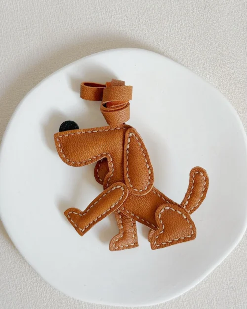 A playful dog bag charm handcrafted from French goatskin leather. Hand-stitched over three days and gift boxed, perfect for bags, keys, or car keys.