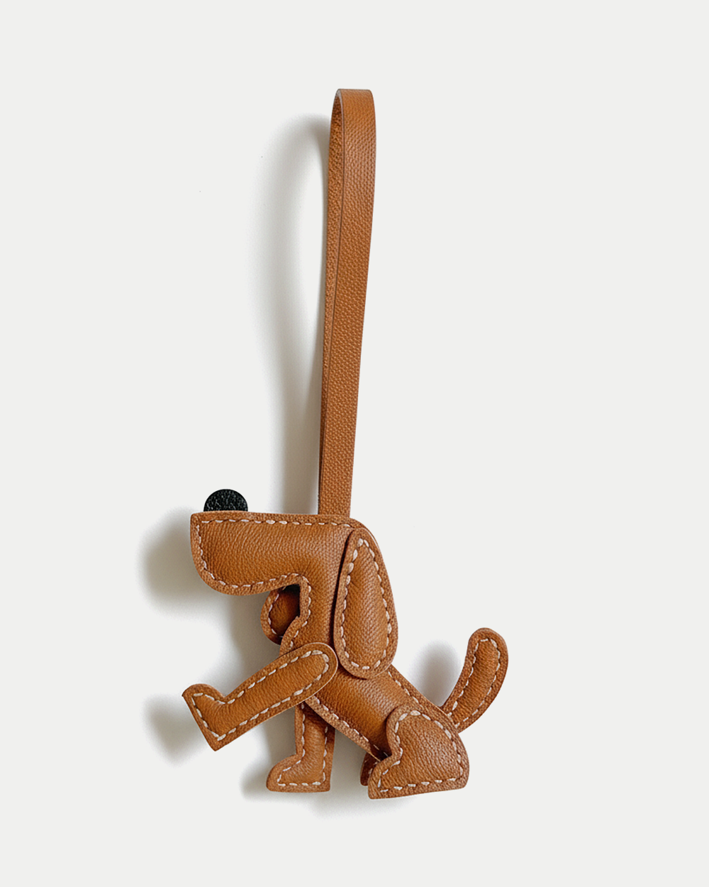 A playful dog bag charm handcrafted from French goatskin leather. Hand-stitched over three days and gift boxed, perfect for bags, keys, or car keys.