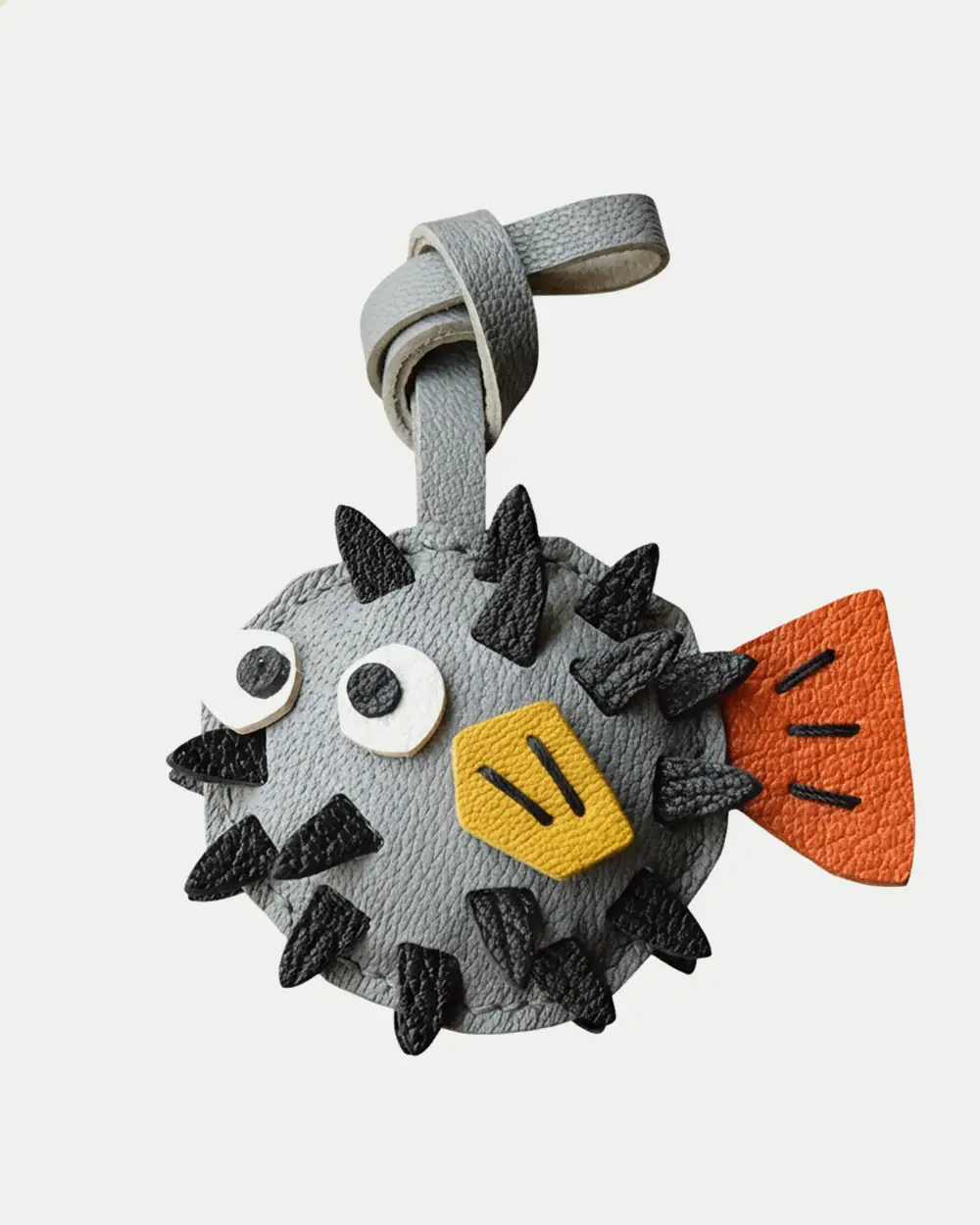A whimsical pufferfish bag charm handcrafted from French goatskin leather. Hand-stitched over three days and gift boxed for bags, keys, or car keys.