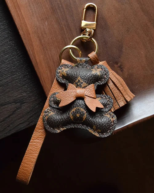 A playful bow bear bag charm handcrafted from French goatskin leather. Hand-stitched over three days and gift boxed for bags, keys, or car keys.