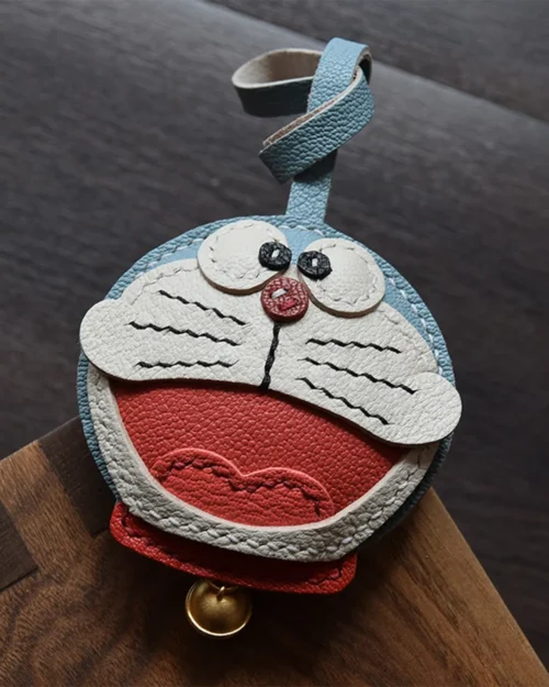 A playful Doraemon bag charm handcrafted from French goatskin leather. Hand-stitched over three days and gift boxed, perfect for bags, keys, or car keys.