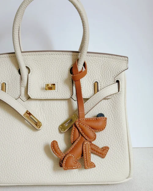 A playful dog bag charm handcrafted from French goatskin leather. Hand-stitched over three days and gift boxed, perfect for bags, keys, or car keys.