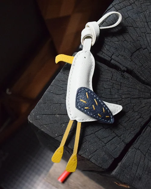 A whimsical seagull bag charm handcrafted from French goatskin leather. Hand-stitched over three days and gift boxed for bags, keys, or car keys.